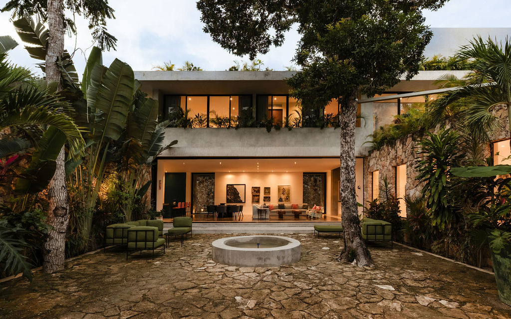 Casa Xolo's stone courtyard and open living room glowing at dusk