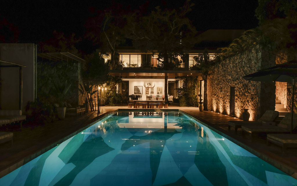 Casa Xolo lit at night, pool glowing in front of the villa